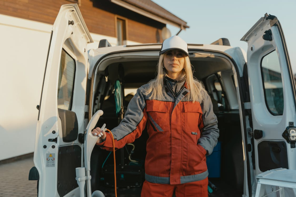 An image of a woman in orange clothes standing near a van