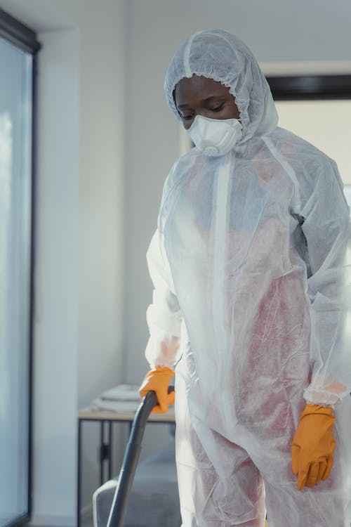 A photo of a person wearing a PPE suit and holding pest control equipment