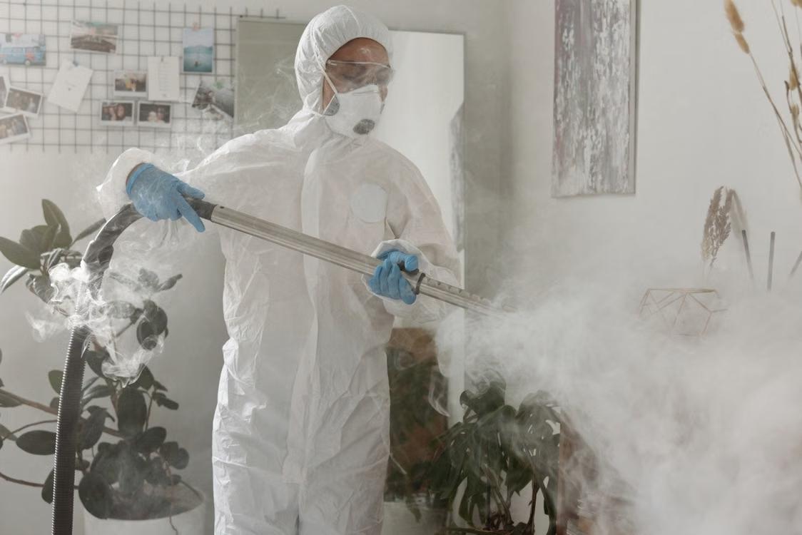 a person wearing a protective suit fumigating a room