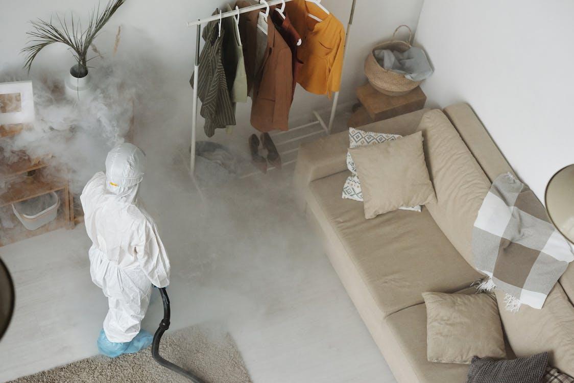 An image of an exterminator wearing a protective suit and holding equipment
